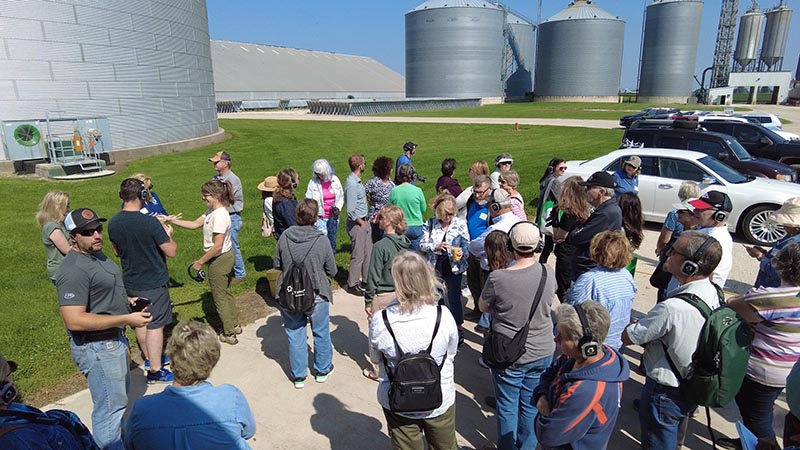Tour goers hear how CHS Elburn Co-op operates, with grain bins in the background.