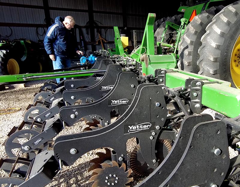 Joe Rothermel in upper left works on a pump, black equipment attached to green tractor.